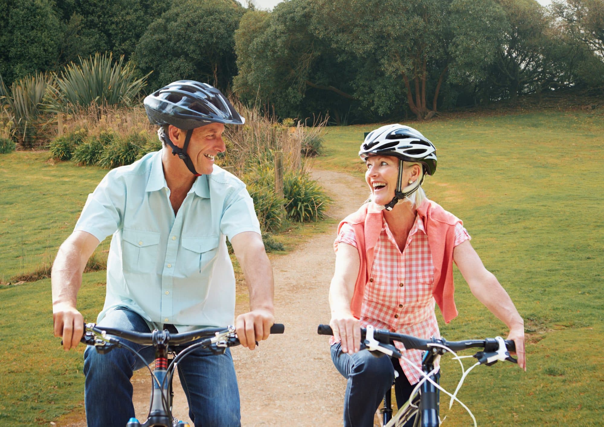 A couple laughing together as they ride bikes along a New Zealand cycle path